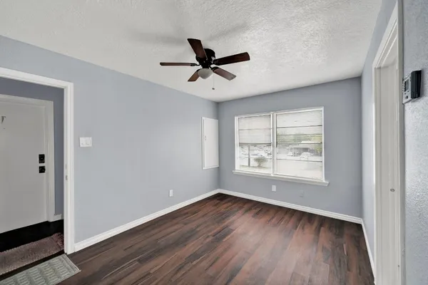 a view of an empty room with wooden floor and a window