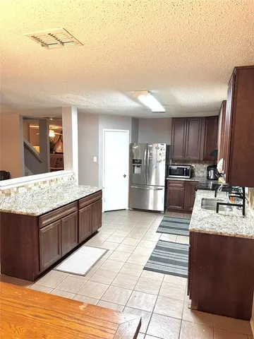 a large kitchen with granite countertop a large counter top and wooden cabinets