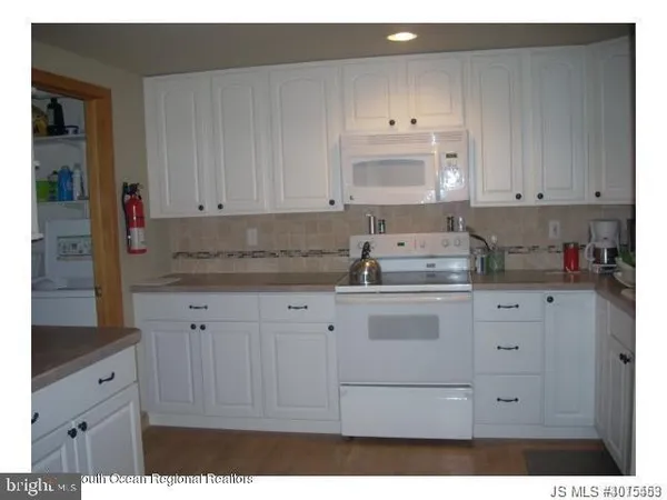 a kitchen with granite countertop white cabinets and white appliances