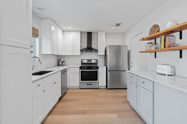 a kitchen with a sink white cabinets and stainless steel appliances