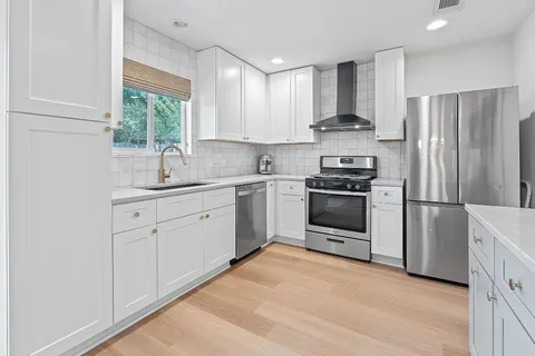 a kitchen with stainless steel appliances granite countertop white cabinets and a stove top oven
