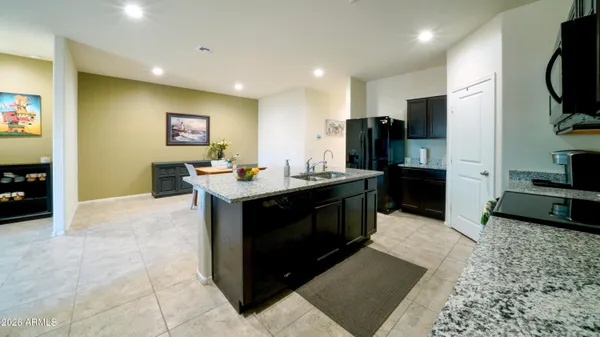 a kitchen with stainless steel appliances kitchen island granite countertop a sink and a refrigerator