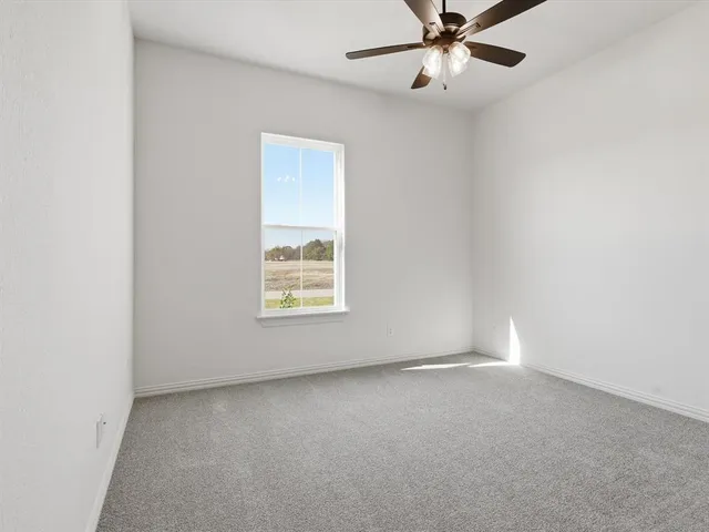 an empty room with a window and ceiling fan