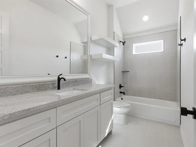 a bathroom with a granite countertop sink a toilet and shower