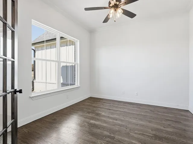 an empty room with wooden floor fan and windows