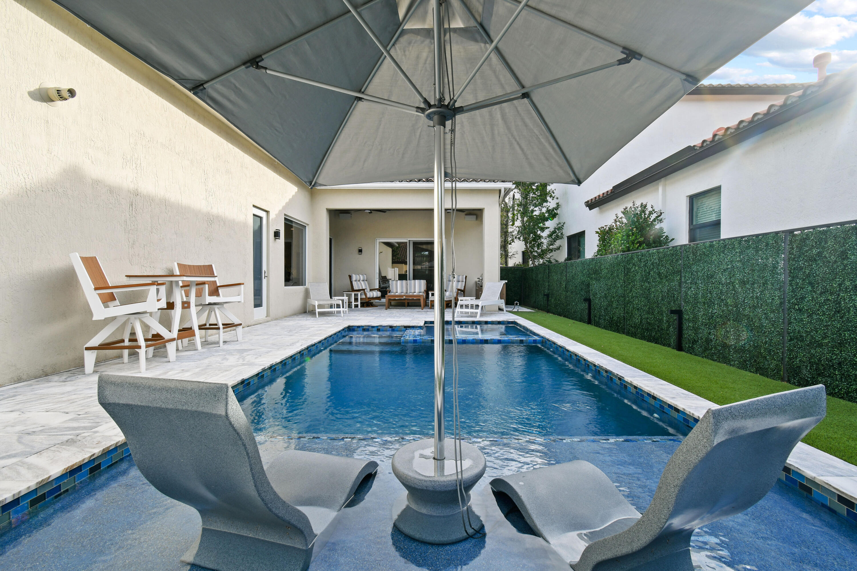 123 Barcelona Drive Jupiter, FL 33458 - Photo 42 of 59 a view of a patio with chairs and table under an umbrella