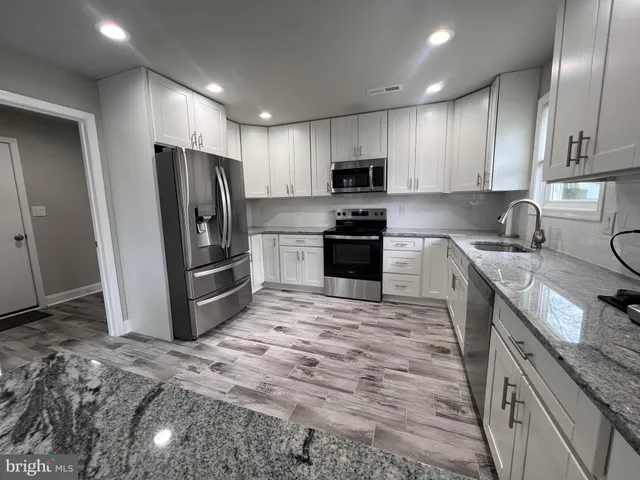 a kitchen with stainless steel appliances granite countertop a stove a sink and a refrigerator