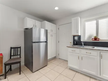 a kitchen with white cabinets and refrigerator