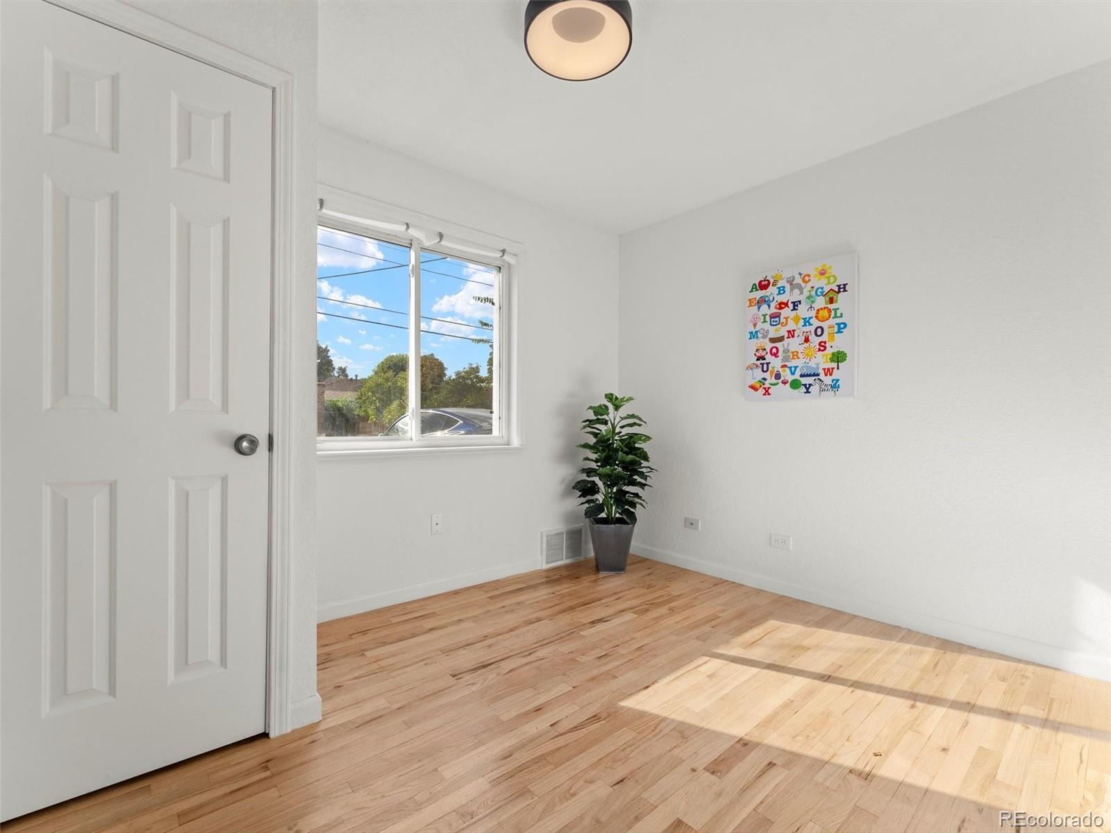 2865 Quebec Street Denver, CO 80207 - Photo 12 of 30 a view of an empty room with wooden floor and a window