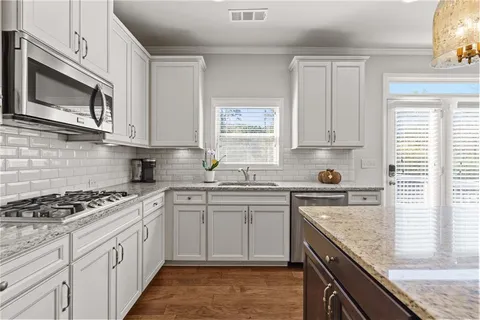 a kitchen with granite countertop a sink cabinets and stainless steel appliances