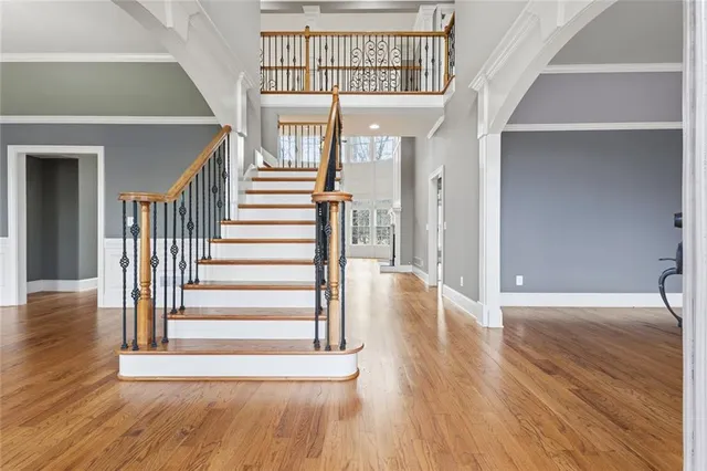 a view of an empty room with wooden floor fireplace and a window