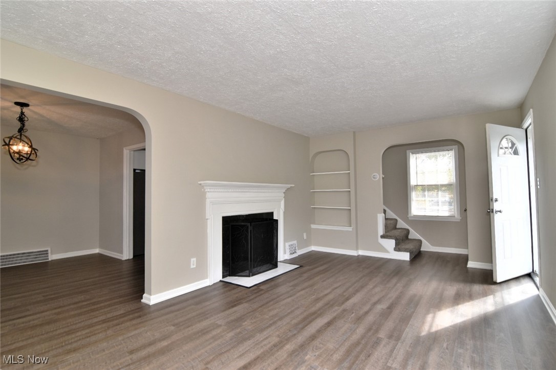 1443 Churchill Road Lyndhurst, OH 44124 - Photo 5 of 39 Unfurnished living room featuring built in shelves, a fireplace, arched walkways, stairs, and wood finished floors