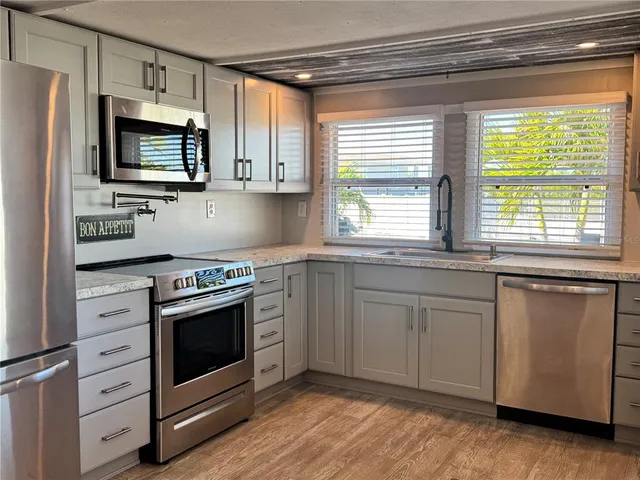 a kitchen with granite countertop white cabinets stainless steel appliances and window