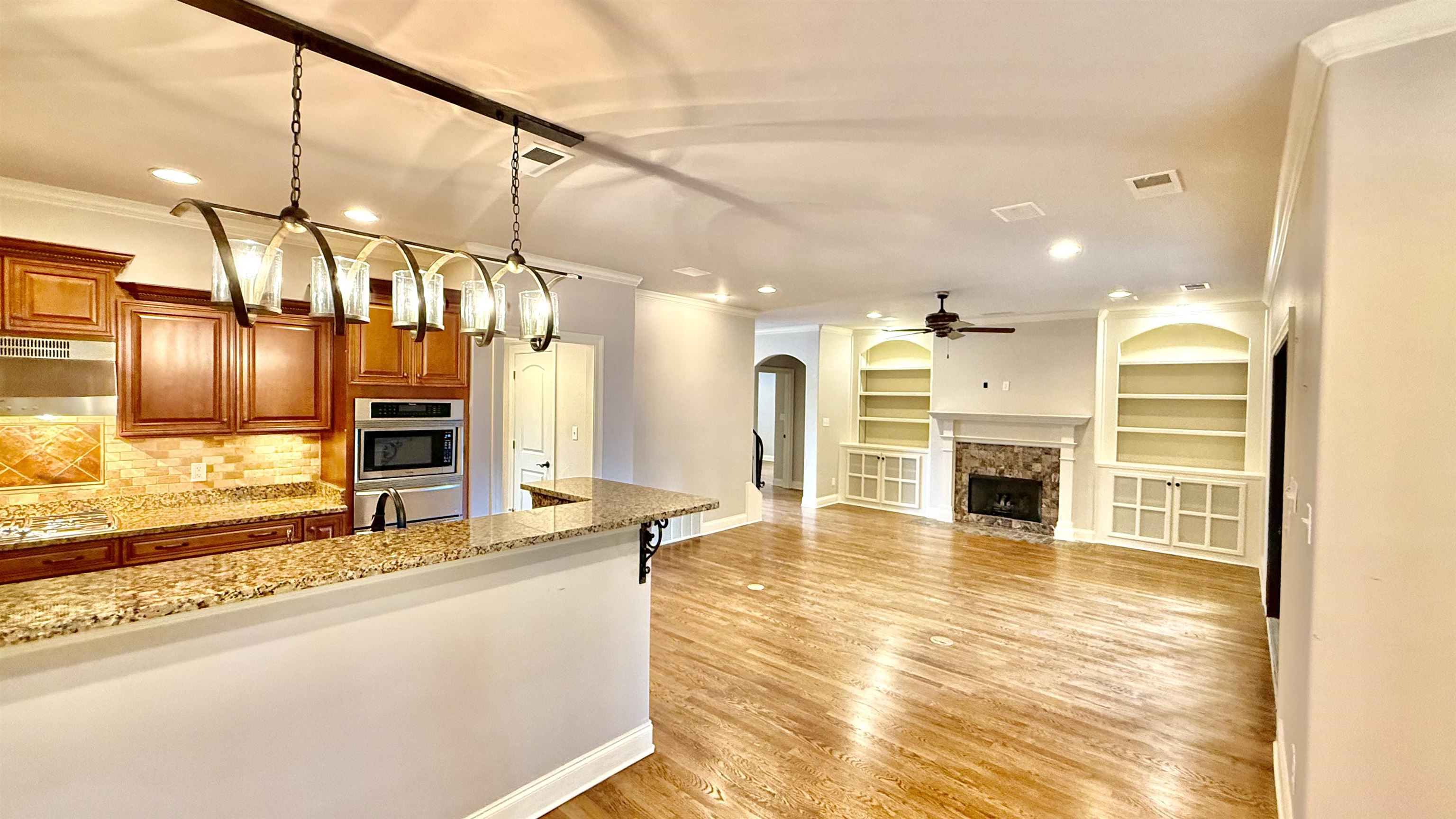 247 South Greer Street Memphis, TN 38111 - Photo 8 of 29 Kitchen featuring brown cabinetry, light stone countertops, arched walkways, ornamental molding, and pendant lighting