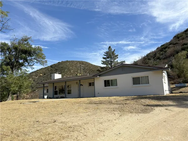 a front view of house with yard and trees in the background