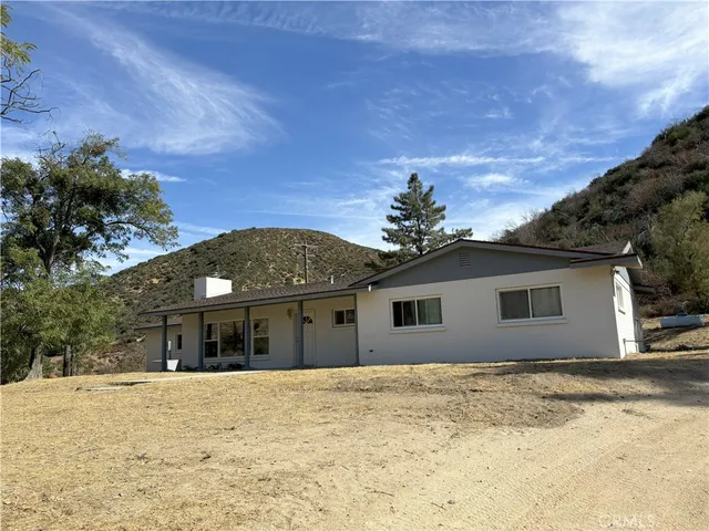 a front view of house with yard and trees in the background