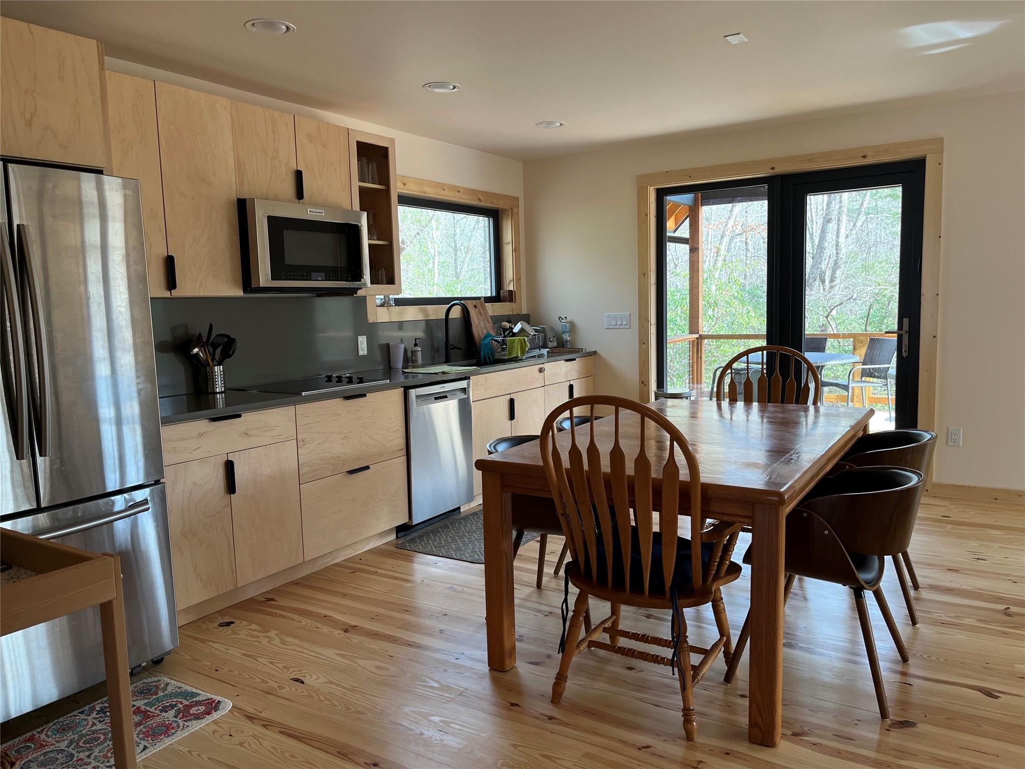 1252 Cardinal Road Brevard, NC 28712 - Photo 5 of 31 a kitchen with stainless steel appliances granite countertop a stove a refrigerator a sink a dining table and chairs with wooden floor