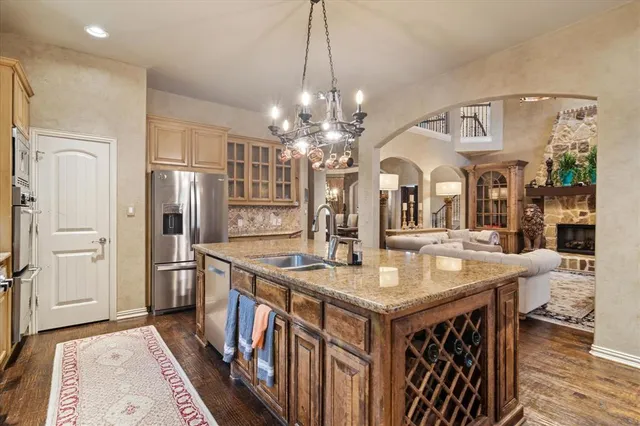 a kitchen with stainless steel appliances granite countertop a kitchen island a refrigerator a stove and a sink