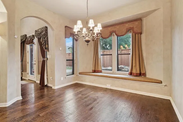 a view of a hallway with wooden floor and a chandelier