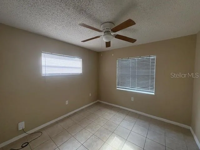 a view of an empty room with window and chandelier fan