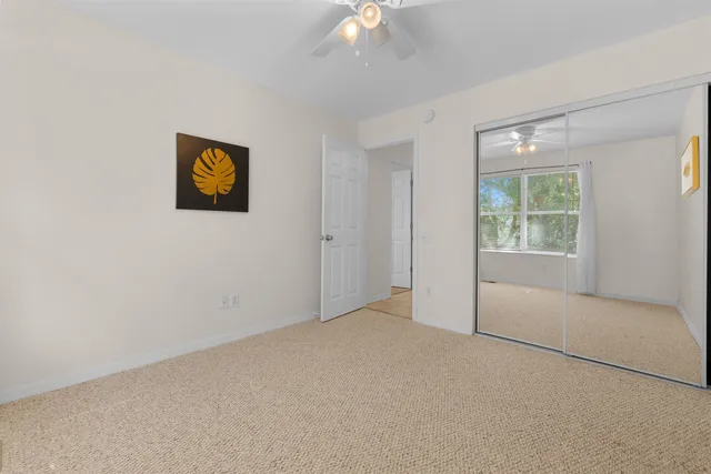 an empty room with windows and chandelier fan