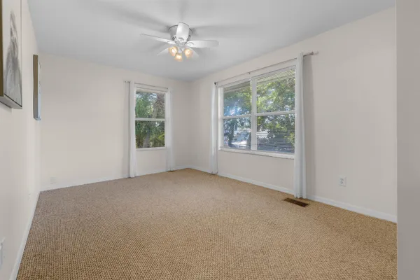 an empty room with windows and fan