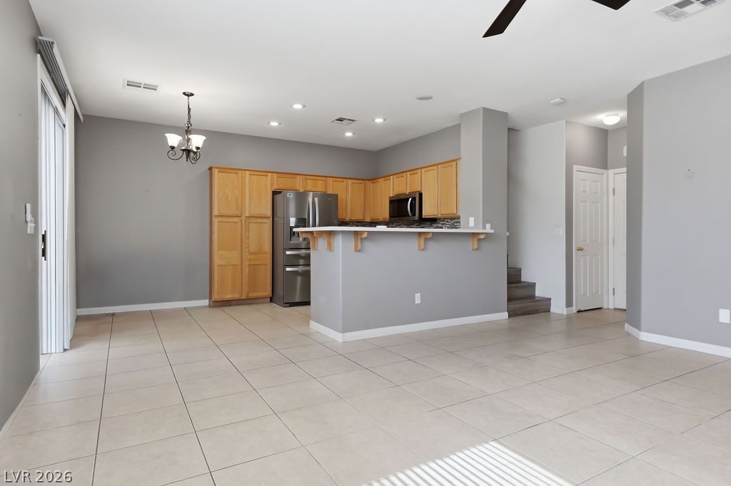 754 Solitude Point Avenue Henderson, NV 89012 - Photo 11 of 38 An open-concept living area with a well-appointed kitchen featuring light wood cabinetry and modern appliances.