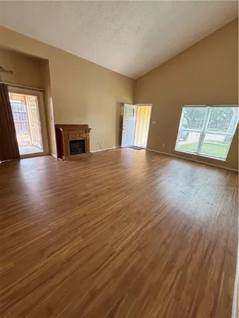 a view of empty room with wooden floor and fireplace