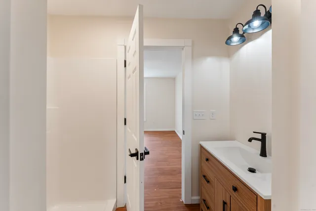 an empty room with wooden floor ceiling fan and windows