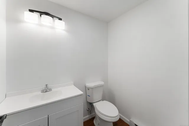 a large kitchen with kitchen island a stove a sink a refrigerator and white cabinets with wooden floor