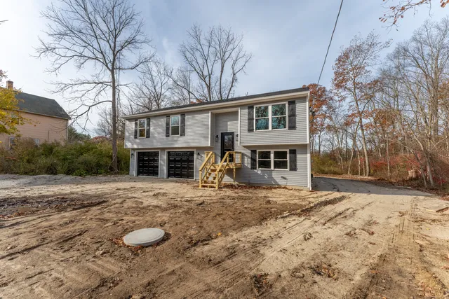 a front view of a house with yard and trees in the background