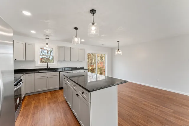 a kitchen with granite countertop a sink stove and wooden floor