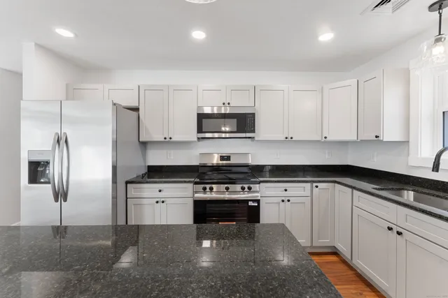 a kitchen with stainless steel appliances granite countertop a stove a sink and a refrigerator