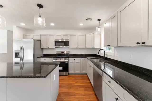 a kitchen with stainless steel appliances granite countertop a sink a stove and a refrigerator