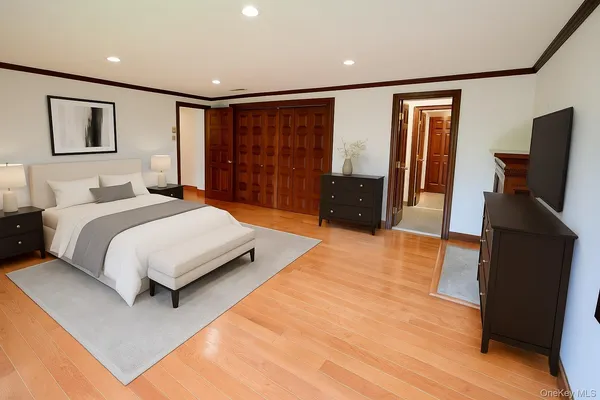 a bedroom with a large bed and a flat tv screen