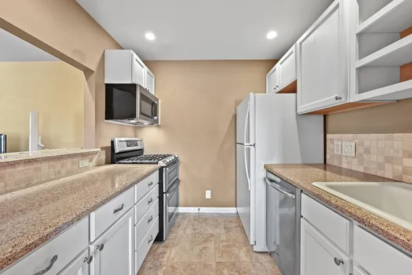 a kitchen with granite countertop a sink a counter top space stainless steel appliances and cabinets