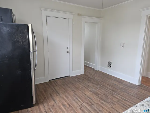 a view of an empty room with wooden floor and closet
