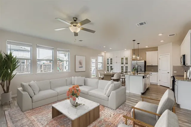 a living room with furniture kitchen view and a large window