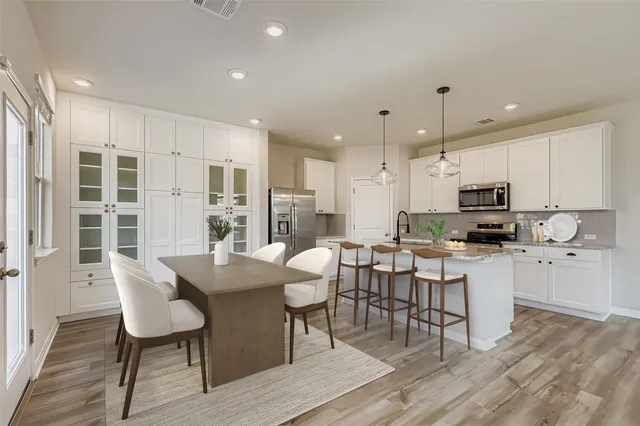 a kitchen with stainless steel appliances granite countertop a stove a sink a refrigerator a dining table and chairs