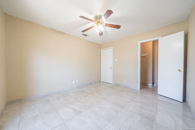 an empty room with closet and ceiling fan