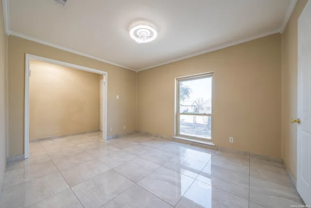 a view of an empty room with window and chandelier fan