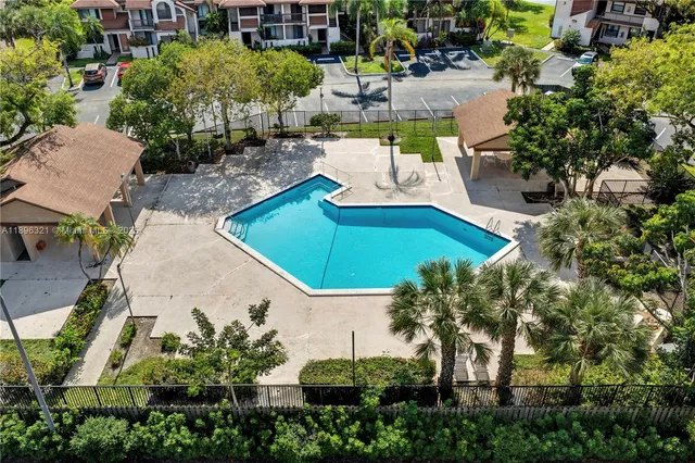 an aerial view of a house with swimming pool and large trees