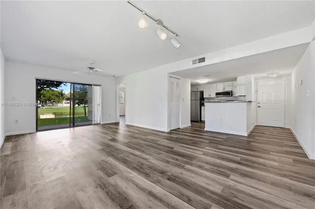 a view of an empty room with a kitchen and a window