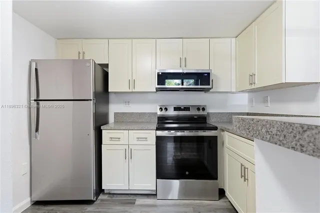 a kitchen with white cabinets and stainless steel appliances