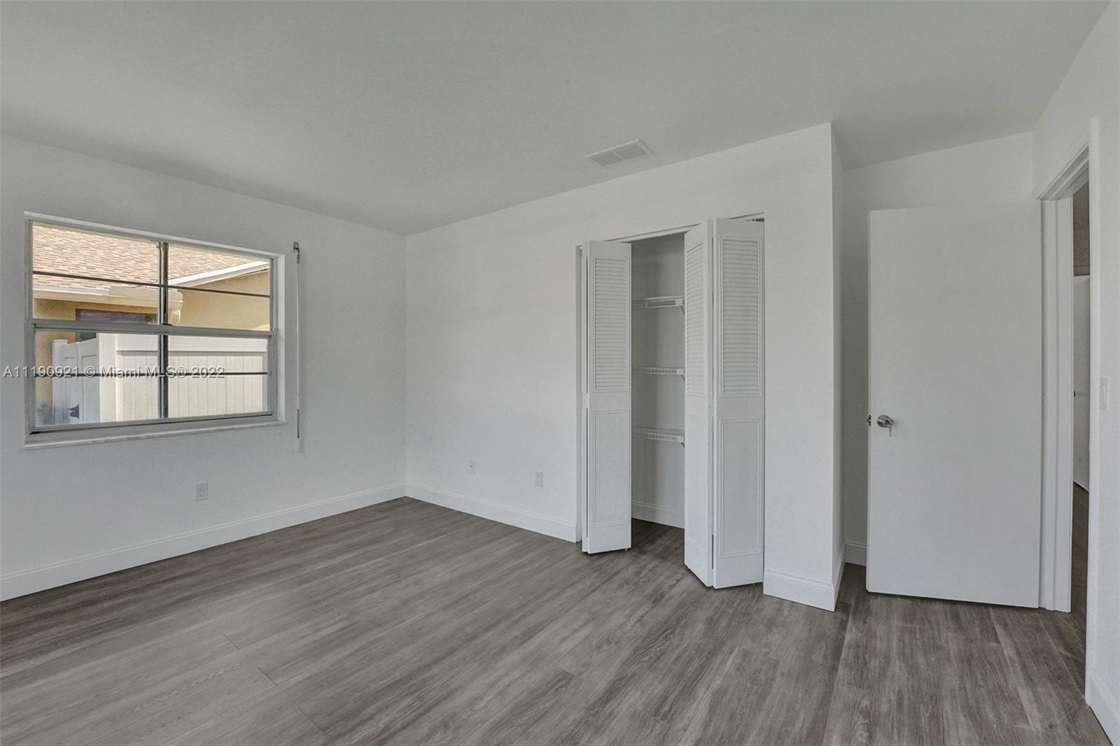 23098 Southwest 55th Avenue Boca Raton, FL 33433 - Photo 20 of 49 an empty room with wooden floor and windows
