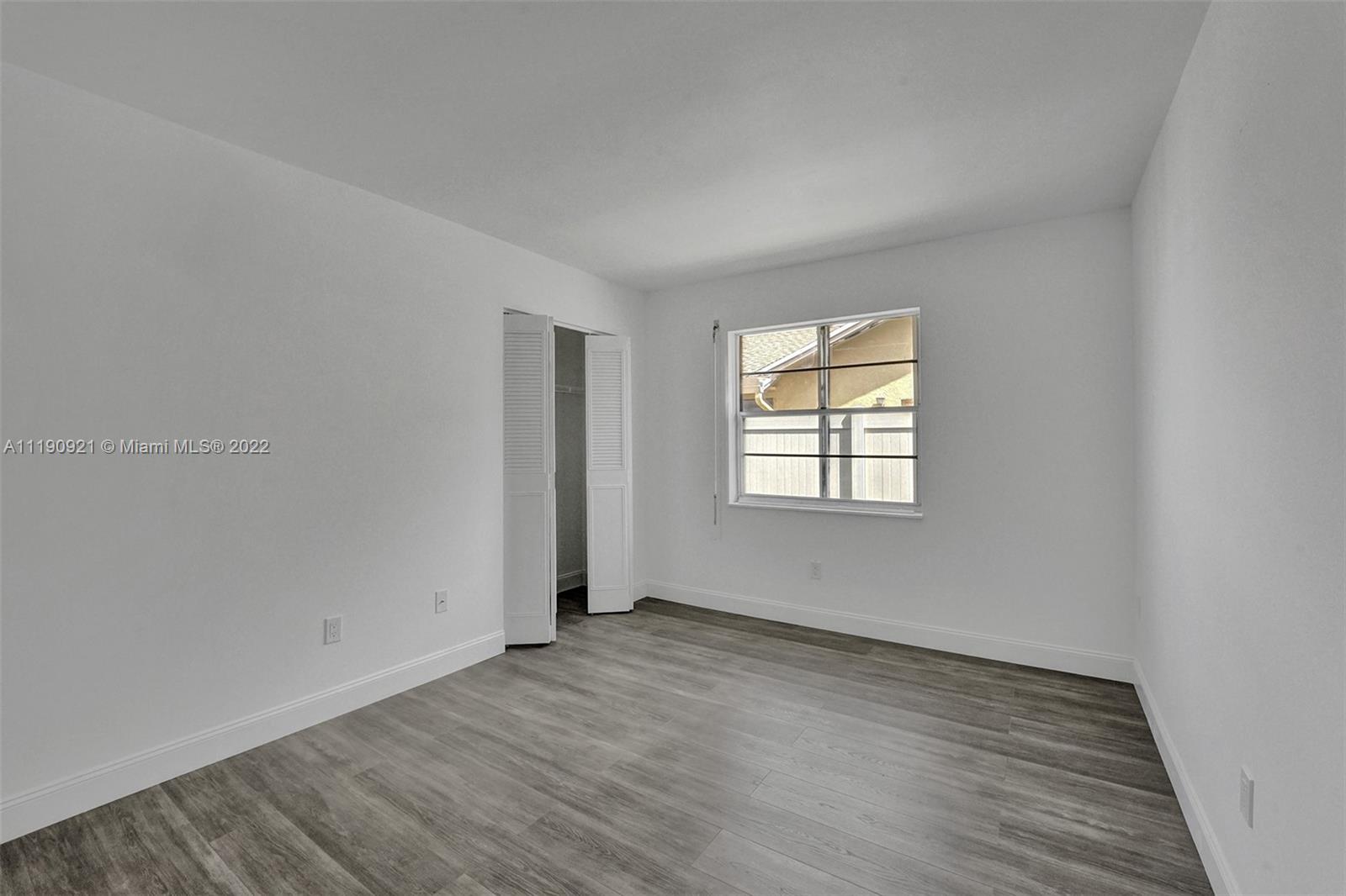 23098 Southwest 55th Avenue Boca Raton, FL 33433 - Photo 24 of 49 an empty room with wooden floor and windows