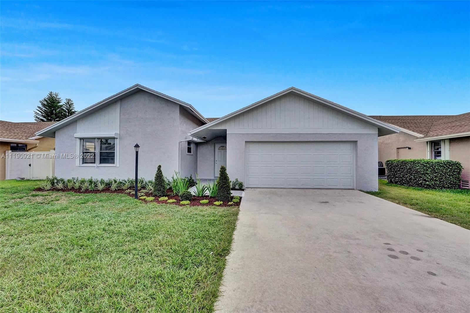 23098 Southwest 55th Avenue Boca Raton, FL 33433 - Photo 40 of 49 a front view of a house with a yard and garage