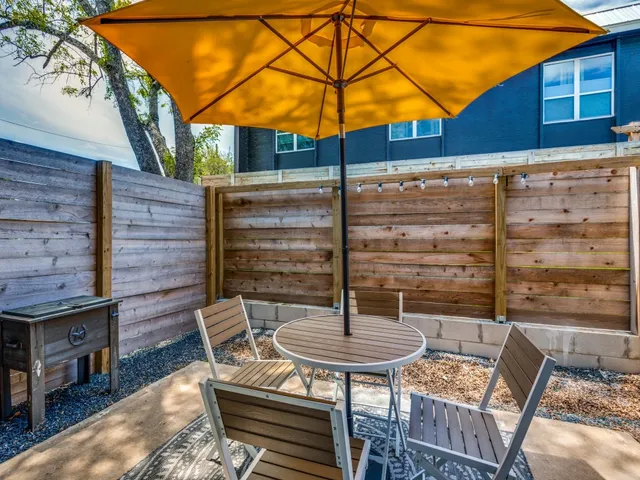 a backyard of a house with wooden fence table and chairs