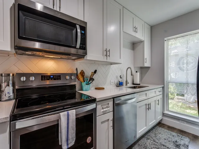 a kitchen with stainless steel appliances a stove a microwave cabinets and a counter space