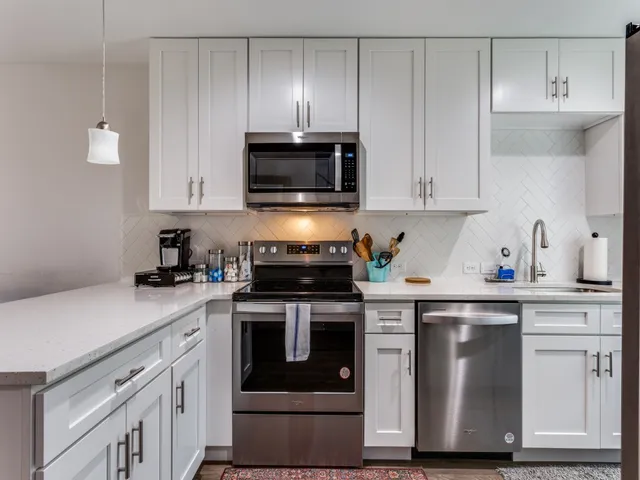 a kitchen with granite countertop white cabinets and stainless steel appliances